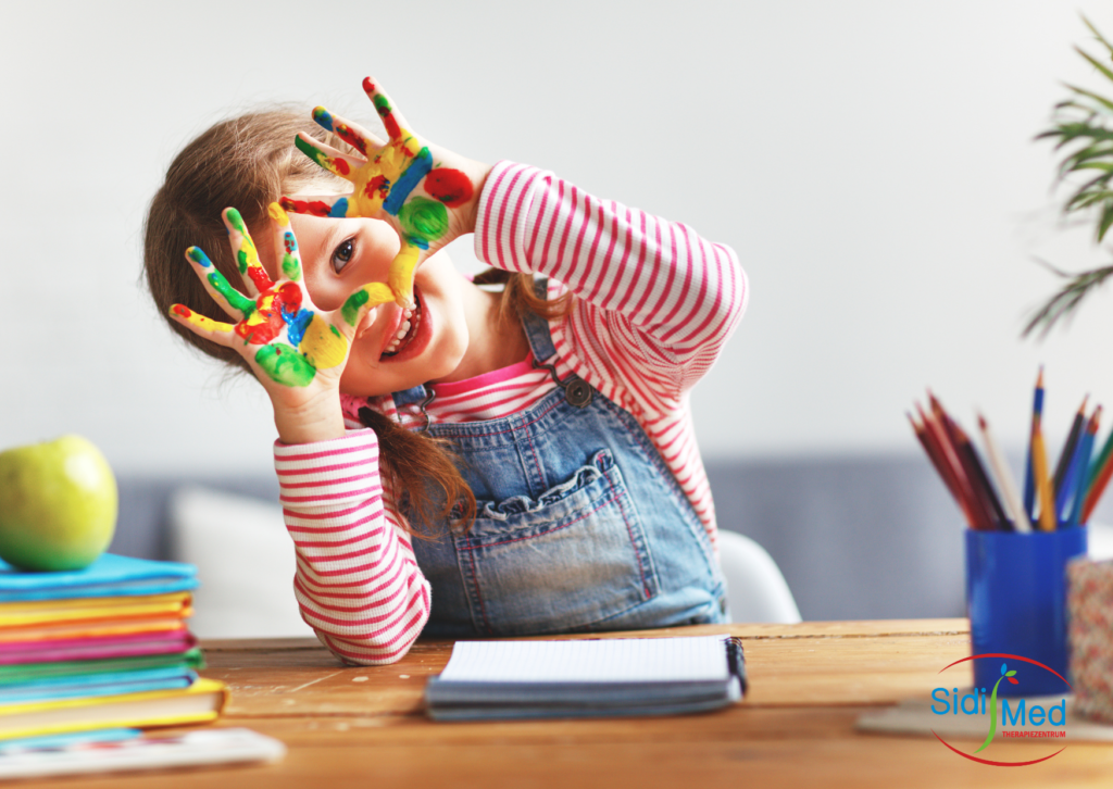 Vorschulkind mit bunt bemalten Fingern